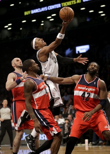 Brooklyn Nets' Paul Pierce, top, scores over Washington Wizards' Marcin Gortat, left, Nene Hilario, right, and Martell Webster during the second half of an NBA basketball game Wednesday, Dec. 18, 2013, in New York. Washington defeated Brooklyn 113-107. (AP Photo/Seth Wenig)