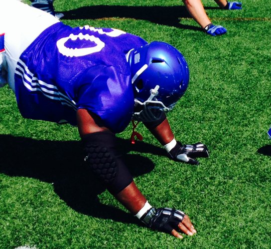 Offensive lineman Keyon Haughton stretches while wearing the shiny gloves. 