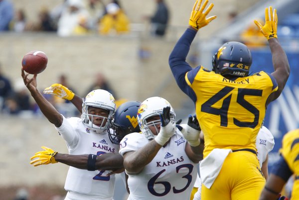 Kansas quarterback Montell Cozart takes a helmet-to-helmet hit from West Virginia safety Karl Joseph while releasing a pass during the second quarter on Saturday, Oct. 4, 2014 at Milan Puskar Stadium in Morgantown, West Virginia. Also pictured are KU offensive lineman Ngalu Fusimalohi and WVU defensive lineman Eric Kinsey.