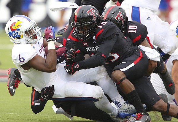 Kansas running back Corey Avery is dropped to the ground by Texas Tech defenders Jalen Barnes (19) and Pete Robertson (10) during the fourth quarter on Saturday, Oct. 18, 2014 at Jones AT&T Stadium in Lubbock, Texas.