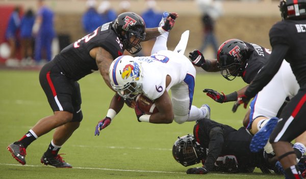 Kansas running back Corey Avery is taken off his feet by several Texas Tech defenders during the first quarter on Saturday, Oct. 18, 2014 at Jones AT&T Stadium in Lubbock, Texas.