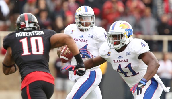 Kansas quarterback Michael Cummings looks to throw as Texas Tech linebacker Pete Robertson is fended off by KU tight end Jimmay Mundine during the second quarter on Saturday, Oct. 18, 2014 at Jones AT&T Stadium in Lubbock, Texas.