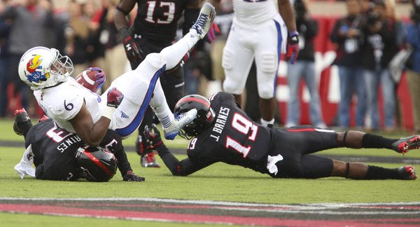 Kansas running back Corey Avery is taken down by Texas Tech defenders J.J. Gaines, left, and Jalen Barnes during the second quarter on Saturday, Oct. 18, 2014 at Jones AT&T Stadium in Lubbock, Texas.