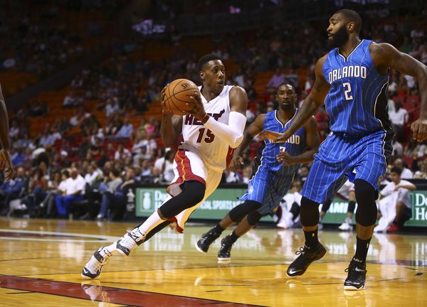 Miami Heat's Mario Chalmers (15) drives around Orlando Magic'sKyle O'Quinn (2) during the first half of a NBA basketball game in Miami, Oct. 7, 2014. (AP Photo/J Pat Carter)
