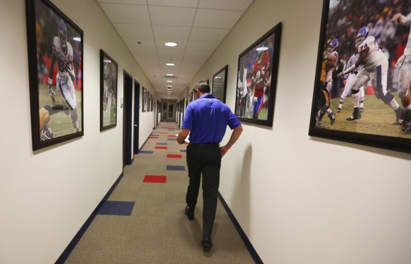Shortly after 6:30 a.m., Kansas interim head football coach Clint Bowen walks toward his office down a hallway lined with rows of images documenting the high points from the program's recent history, Wednesday, Oct. 22, 2014.