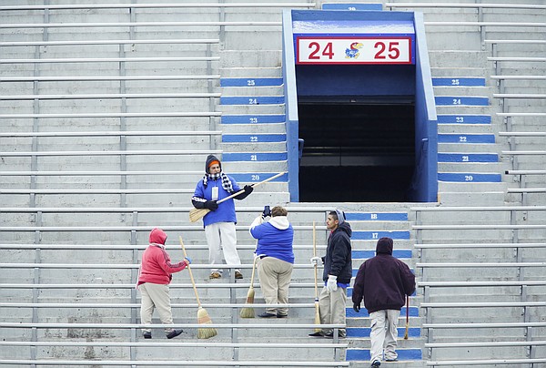 A game day worker has a photo taken of him playing guitar on a broom as crews work to sweep the stands clear of snow prior to kickoff between Kansas and TCU on Saturday, Nov. 15, 2014 at Memorial Stadium.