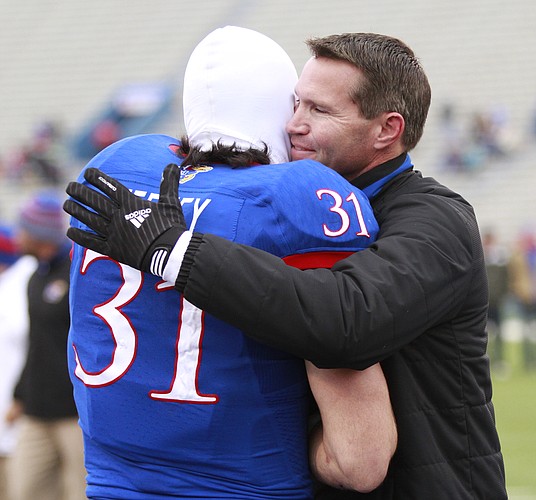 Kansas interim head coach Clint Bowen gives a big hug to senior linebacker Ben Heeney as Heeney is introduced with the rest of the seniors prior to kickoff on Saturday, Nov. 15, 2014 at Memorial Stadium.