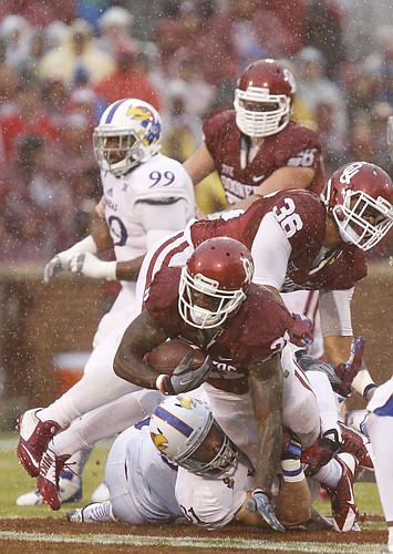 Oklahoma running back Keith Ford (21) dives over Kansas linebacker Ben Heeney (31) for yardage during the first quarter on Saturday, Nov. 22, 2014 at Memorial Stadium in Norman, Oklahoma. Above is OU fullback Dimitri Flowers (36).