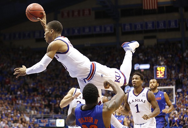 Kansas guard Frank Mason III (0) looks to dump a pass as he bowls over Florida guard Michael Frazier II (20) during the second half on Friday, Dec. 5, 2014 at Allen Fieldhouse.