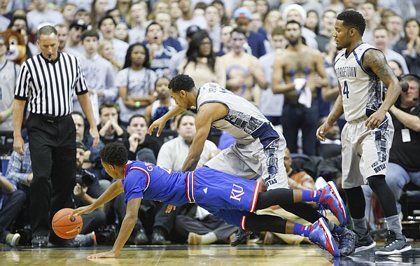 Kansas guard Devonte Graham (4) lays out while competing for a loose ball with Georgetown forward Isaac Copeland (11) during the first half on Wednesday, Dec. 10, 2014 at Verizon Center in Washington D.C. At right is Georgetown guard D'Vauntes Smith-Rivera (4).