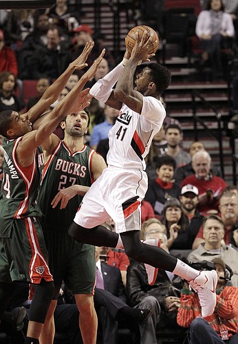 Portland Trail Blazers forward Thomas Robinson, right, shoots against Milwaukee Bucks forward Giannis Antetokounmpo, from Greece, left, and center Zaza Pachulia, from Ukraine, during the first half of an NBA basketball game in Portland, Ore., Wednesday, Dec. 17, 2014.(AP Photo/Don Ryan)
