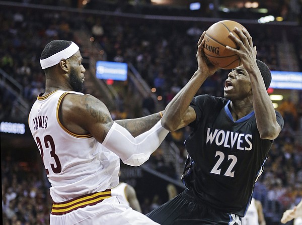 Minnesota Timberwolves' Andrew Wiggins (22) is fouled by Cleveland Cavaliers' LeBron James during the third quarter of an NBA basketball game Tuesday, Dec. 23, 2014, in Cleveland. Wiggins led the Timberwolves with 27 points, but the Cavaliers won 125-104. (AP Photo/Mark Duncan)
