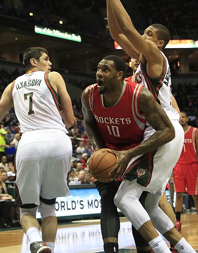Houston Rockets forward Tarik Black, center, drives to the basket against the defense of Milwaukee Bucks guard Giannis Antetokounmpo, right, during the first half of an NBA basketball game Saturday, Nov. 29, 2014, in Milwaukee. (AP Photo/Darren Hauck)
