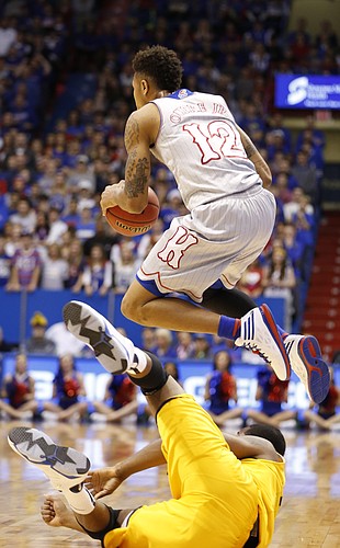 Kansas guard Kelly Oubre Jr. (12) jumps over Kent State center Khaliq Spicer (21) to save a loose ball during the first half on Tuesday, Dec. 30, 2014 at Allen Fieldhouse.