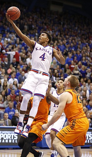 Kansas guard Devonte Graham (4) floats in for a bucket over Oklahoma State guard Phil Forte III (13) during the first half, Tuesday, Jan. 13, 2015 at Allen Fieldhouse.