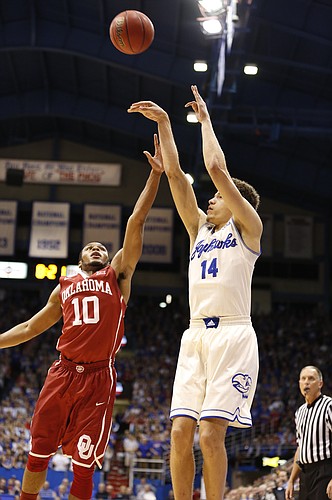 Kansas guard Brannen Greene (14) puts up a three from the corner as he is defended by Oklahoma guard Jordan Woodard (10) during the first half on Monday, Jan. 19, 2015 at Allen Fieldhouse.