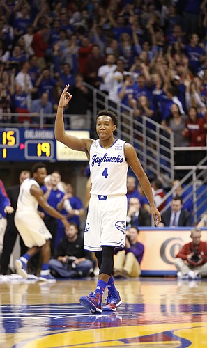 Kansas guard Devonte Graham (4) holds up three fingers to celebrate his shot beyond the arc that shot high off the rim and down through the net during the first half on Monday, Jan. 19, 2015 at Allen Fieldhouse.