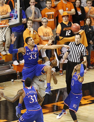 Kansas forward Landen Lucas (33) sends away a shot from Oklahoma State guard Anthony Hickey Jr. (12) during the first half on Saturday, Feb. 7, 2015 at Gallagher-Iba Arena. Also pictured are Kansas guard Frank Mason III (0) and forward Jamari Traylor.