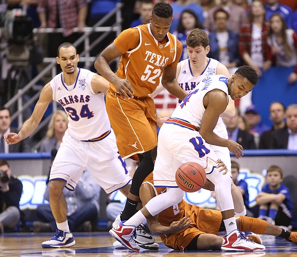 Kansas guard Devonte Graham looks for a loose ball with Texas forward Myles Turner (52) and teammate Perry Ellis during the first half on Saturday, Feb. 28, 2015 at Allen Fieldhouse.