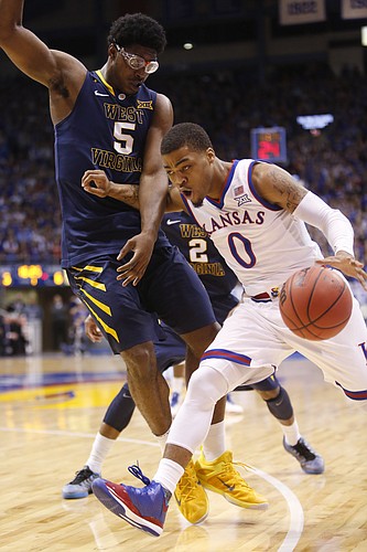 Kansas guard Frank Mason III (0) drives around West Virginia forward Devin Williams (5) during the Jayhawks game against the West Virginia Mountaineers Tuesday, March 4, 2015 at Allen Fieldhouse.
