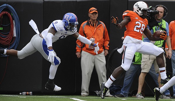 Oklahoma State wide receiver James Washington (28) tries to stay in bounds as he is trailed by Kansas safety Fish Smithson (9) during the first quarter on Saturday, Oct. 24, 2015 at T. Boone Pickens Stadium in Stillwater, Okla.