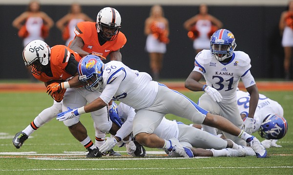Kansas defensive end Anthony Olobia (56) delivers a hit to Oklahoma State running back Raymond Taylor (30) during the fourth quarter on Saturday, Oct. 24, 2015 at T. Boone Pickens Stadium in Stillwater, Okla.