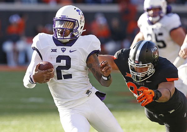 TCU quarterback Trevone Boykin (2) avoids a tackle by Oklahoma State’s Trace Clark, right, during the Cowboys’ 49-29 win Saturday in Stillwater, Oklahoma. The Horned Frogs host Kansas at 11 a.m. Saturday at Amon G. Carter Stadium in Fort Worth, Texas.
