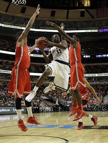 Michigan State's Lourawls Nairn Jr. (11) passes as he drives between Ohio State's Amir Williams, left, and Jae'Sean Tate, right, in the first half of an NCAA college basketball game in the quarterfinals of the Big Ten Conference tournament in Chicago, Friday, March 13, 2015. (AP Photo/Nam Y. Huh)
