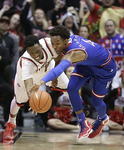 Kansas guard Devonte' Graham (4) and San Diego State guard Dakarai Allen (4) battle for a loose ball during the first half, Tuesday, Dec. 22, 2015 at Viejas Arena in San Diego.