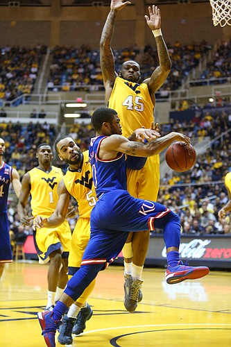 Kansas guard Frank Mason III, drives beneath West Virginia forward Elijah Macon (45) and is fouled by West Virginia guard Jaysean Paige (5), right, in the Jayhawks 74-63 loss to the Mountaineers at the WVU Colliseum in Morgantown, W.V. Tuesday.