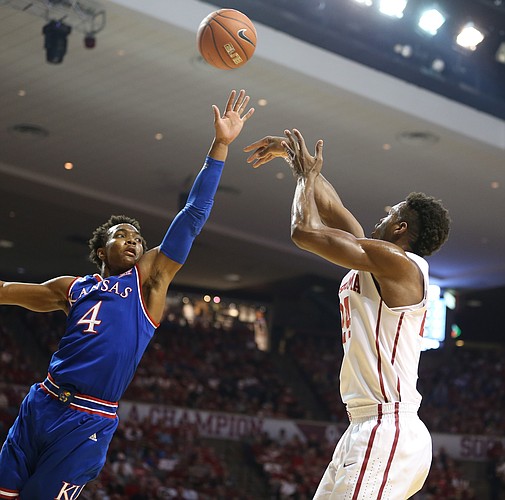 Kansas guard Devonte' Graham (4) lunges to defend against a three from Oklahoma guard Buddy Hield (24) during the first half, Saturday, Feb. 13, 2016 at Lloyd Noble Center in Norman, Okla.