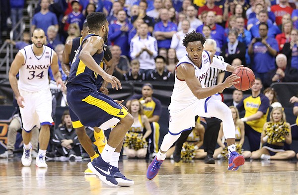 Kansas guard Devonte' Graham (4) pushes the ball up the court against West Virginia guard Tarik Phillip during the second half, Saturday, March 12, 2016 at Sprint Center in Kansas City, Mo.