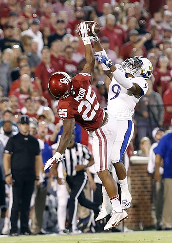 Oklahoma running back Joe Mixon (25) works to make a catch as Kansas safety Fish Smithson (9) defends during the first half of an NCAA college football game in Norman, Okla., Saturday, Oct.29, 2016.