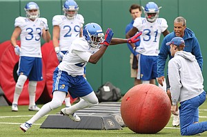 Kansas linebacker Kyron Johnson sweeps aside an obstacle during spring football practice on Tuesday, March 28, 2017.