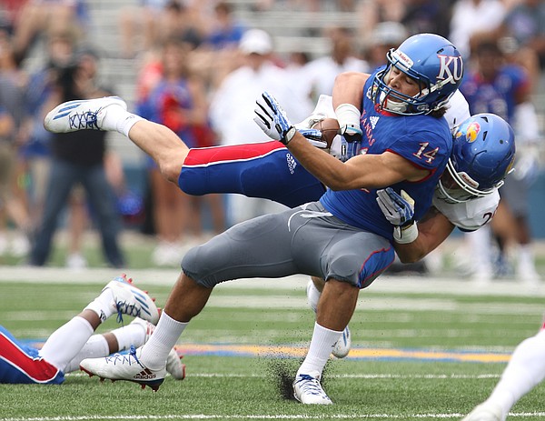 Team KU receiver Kerr Johnson Jr. (14) is taken to the turf by Team Jayhawk linebacker Joe Dineen Jr. (29) during the first quarter of the 2017 Spring Game on Saturday, April 15 at Memorial Stadium.