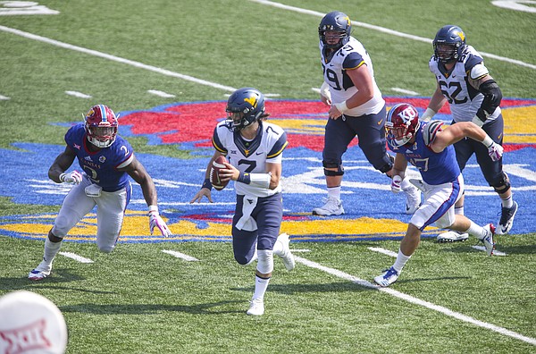 West Virginia quarterback Will Grier (7) scrambles for a long run between Kansas defensive end Dorance Armstrong Jr. (2) and Kansas linebacker Keith Loneker Jr. (47) during the fourth quarter on Saturday, Sept. 23, 2017 at Memorial Stadium.