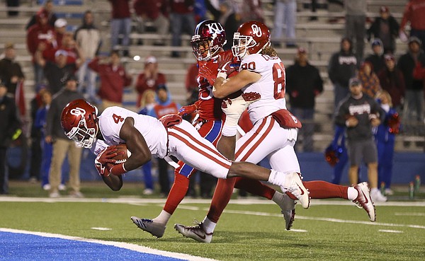 Kansas cornerback Hasan Defense (13) is pushed aside by Oklahoma tight end Grant Calcaterra (80) as Oklahoma running back Trey Sermon (4) dives into the end zone for a touchdown during the fourth quarter on Saturday, Nov. 18, 2017 at Memorial Stadium.