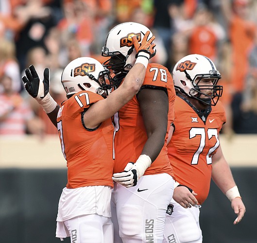 Oklahoma State wide receiver Dillon Stoner (17) celebrates his 76 yard touchdown with offensive linemen Aaron Cochran (78) and Johnny Wilson (72) during the first half of an NCAA college football game with Kansas in Stillwater, Okla., Saturday, Nov. 25, 2017.