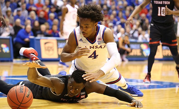 Kansas guard Devonte' Graham (4) and Texas Tech center Norense Odiase (32) dive for a ball during the first half, Tuesday, Jan. 2, 2018 at Allen Fieldhouse.