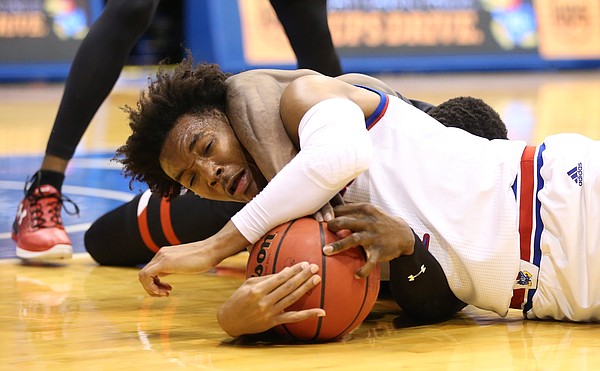 Kansas guard Devonte' Graham (4) gets caught in a stranglehold by Texas Tech center Norense Odiase (32) while tied up for a loose ball during the first half, Tuesday, Jan. 2, 2018 at Allen Fieldhouse.