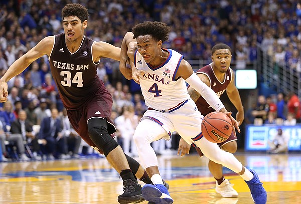 Kansas guard Devonte' Graham (4) tries to shrug off Texas A&M center Tyler Davis (34) on his way to the bucket during the first half, Saturday, Jan. 27, 2018 at Allen Fieldhouse.
