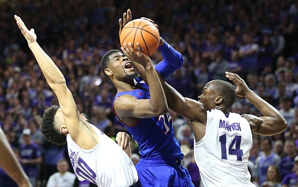 Kansas guard Malik Newman (14) gets a shot off as he is fouled by Kansas State forward Makol Mawien (14) during the second half, Monday, Jan. 29, 2018 at Bramlage Coliseum in Manhattan, Kan. At left is Kansas State guard Mike McGuirl (00).