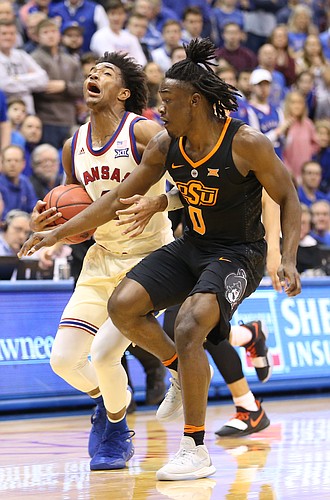 Kansas guard Devonte' Graham (4) is fouled by Oklahoma State guard Brandon Averette (0) during the second half, Saturday, Feb. 3, 2018 at Allen Fieldhouse.