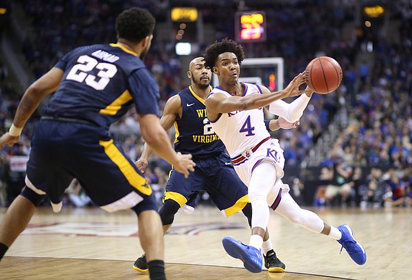 Kansas guard Devonte' Graham (4) pushes the ball to the wing past West Virginia guard Jevon Carter (2) and West Virginia forward Esa Ahmad (23) during the first half, Saturday, March 10, 2018 at Sprint Center in Kansas City, Mo.