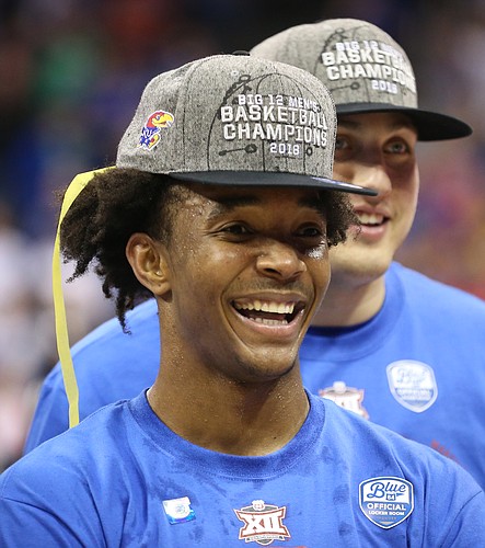 Kansas guard Devonte' Graham (4) smiles as he watches highlights from the Big 12 Tournament following the JayhawksÕ 81-70 win over the Mountaineers in the championship game of the Big 12 Tournament, Saturday, March 10, 2018 at Sprint Center in Kansas City, Mo.