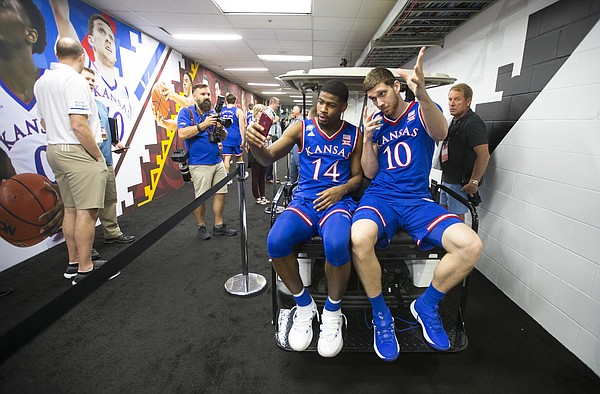 Kansas guard Malik Newman (14) records a video of himself and Kansas guard Sviatoslav Mykhailiuk (10) catching a lift on a golf cart to interviews with CBS on Thursday, March 29, 2018 at the Alamodome in San Antonio, Texas.