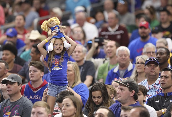 Kansas fan Bristyn Young, San Antonio, hoists up a KU cheerleader doll as she watches the Jayhawks' practice on Friday, March 30, 2018 at the Alamodome in San Antonio, Texas.