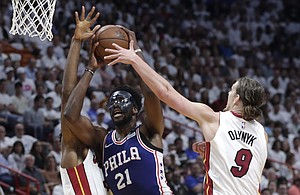 Philadelphia 76ers' Joel Embiid (21) drives to the basket as Miami Heat's Hassan Whiteside, left, and Kelly Olynyk (9) defend during the first half of Game 3 of a first-round NBA basketball playoff series Thursday, April 19, 2018, in Miami. (AP Photo/Lynne Sladky)