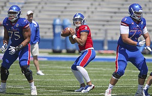 Kansas quarterback Miles Kendrick drops back to throw as he is protected by Kansas offensive lineman Antione Frazier (75) and Kansas offensive lineman Larry Hughes (73) during an open practice on Saturday, April 28, 2018 at Memorial Stadium.