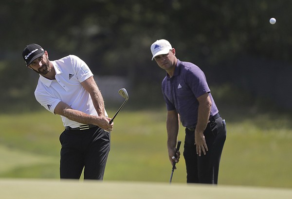 Dustin Johnson chips onto the second green as Gary Woodland looks on during a practice round for the U.S. Open Golf Championship, Monday, June 11, 2018, in Southampton, N.Y. (AP Photo/Julie Jacobson)

